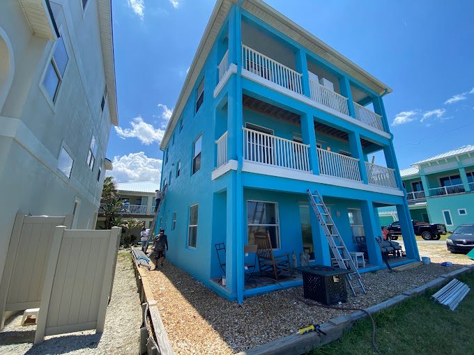Bright blue three-story beach house with white porches and railings