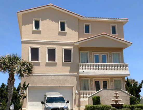 Tan multi-story beach house with painted stucco and white architectural trim