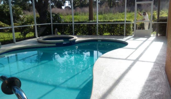 Textured light pool deck coating around a screened residential pool and spa